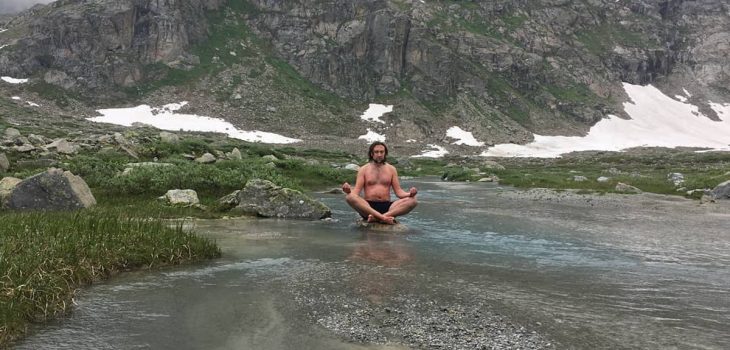 Marius Helf practicing the Wim Hof Method in an icy river surrounded by snow covered mountains